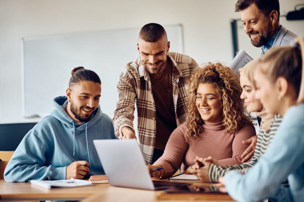 happy college students and their teacher using computer in the classroom